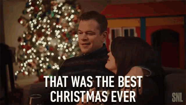 a man and woman are sitting in front of a christmas tree with the caption that was the best christmas ever snl