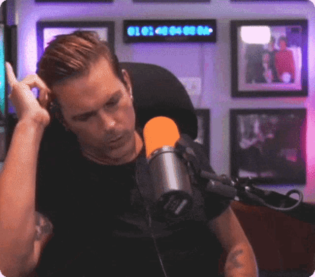 a man sitting in front of a microphone with a clock behind him that says 01 40 04 00 00