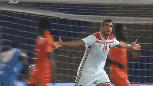 a soccer player in a white jersey with the number 14 on it