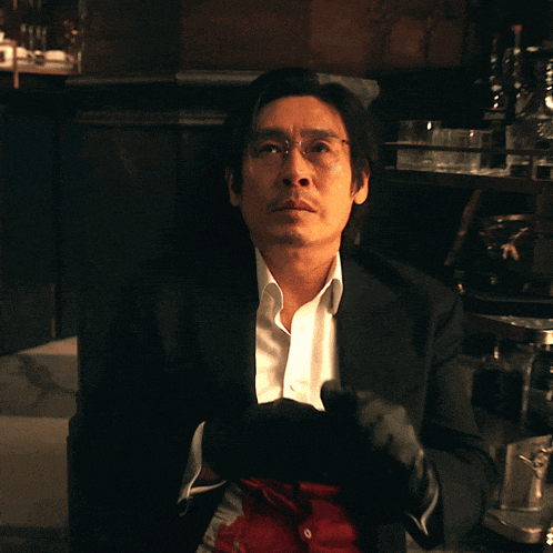 a man in a black suit and white shirt has blood on his shirt