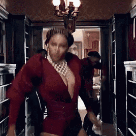 a woman in a red dress and a crown is dancing in a room .