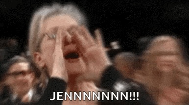 a woman is screaming in a crowd of people and covering her face with her hands .