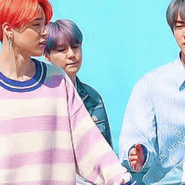 a group of young men standing next to each other with one wearing a pink and white striped sweater