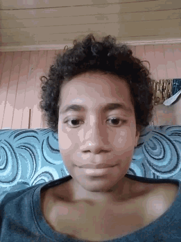 a girl with curly hair is laying on a blue couch