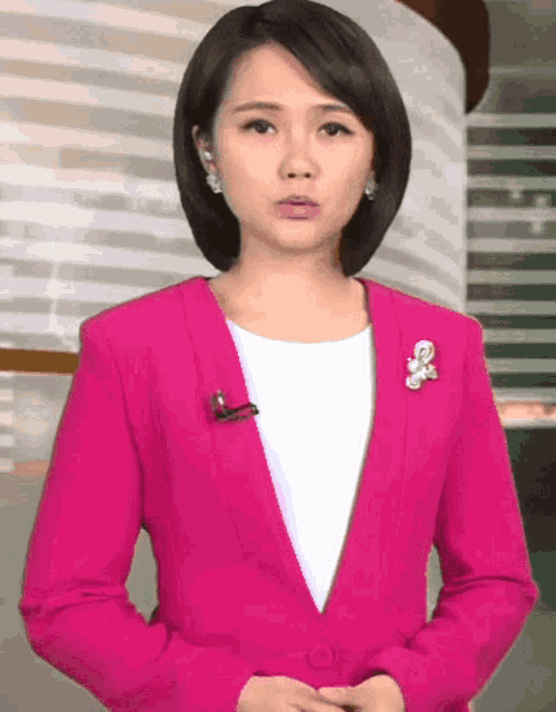 a woman in a pink jacket has a brooch on her collar
