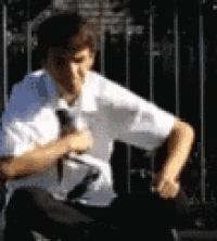 a man in a white shirt and tie is sitting in front of a metal fence .