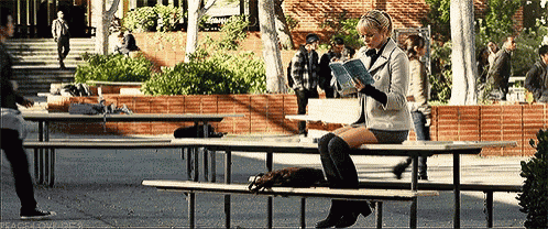 a girl is sitting on a bench reading a book