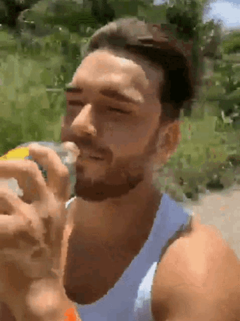 a man with a beard is drinking a soda from a can