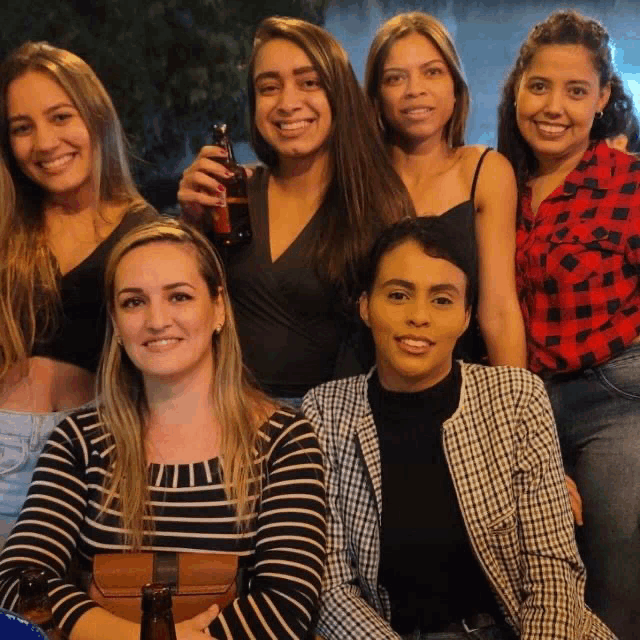 a group of women posing for a picture with one woman holding a bottle