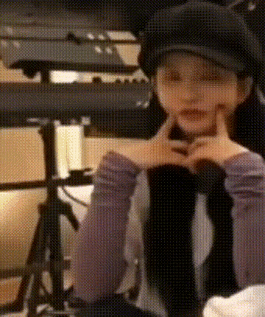 a woman wearing a hat and knee high socks is making a heart shape with her hands