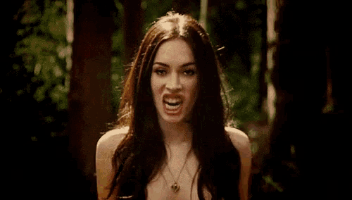 a close up of a woman with a monster 's mouth open in the woods .