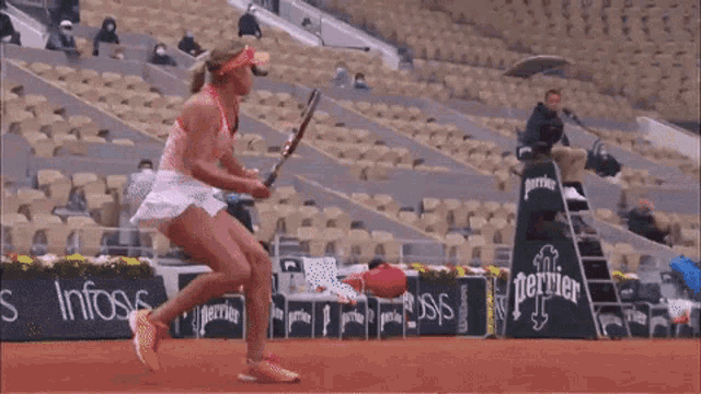 a woman is holding a tennis racquet in front of an emirates fly better sign