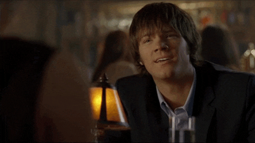 a man in a suit making a funny face while sitting at a table