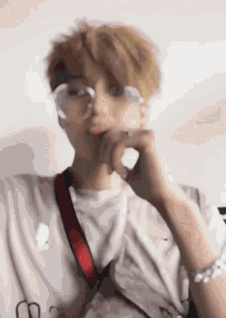 a blurry picture of a young man wearing glasses and a bracelet .