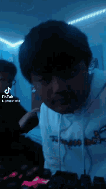 a man in a white hoodie with the word hugs on it is playing a video game