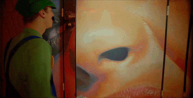 a man in a green hat is looking at a painting of a baby 's nose