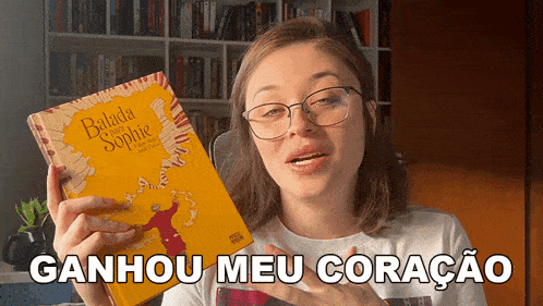 a woman holding a book that says ganhou meu coracao on it