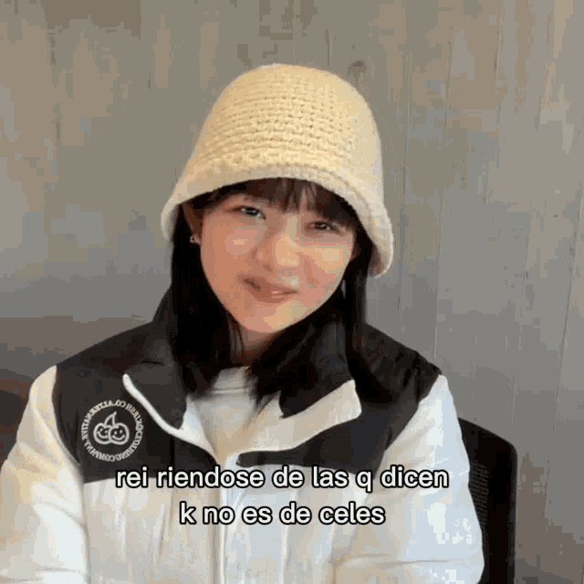 a woman wearing a knitted hat and a white jacket says rei riendose de las q dicen k no es de celes