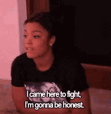 a woman is sitting on a bed and talking about fighting .