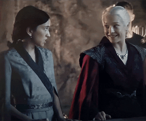 two women standing next to each other with one wearing a red cape