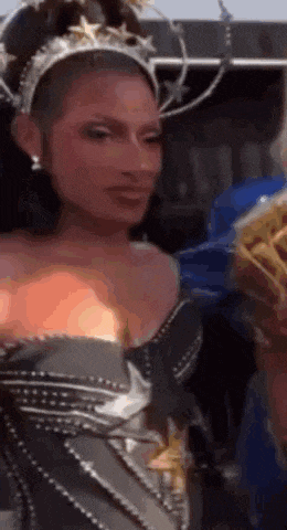 a woman in a costume with a crown on her head is holding a bag of french fries .