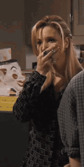 a woman covering her mouth with her hand while standing in a kitchen