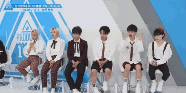 a group of young men are sitting in front of a wall that says produce 101