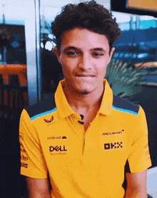 a young man wearing a yellow polo shirt with the word dell on it is making a funny face .