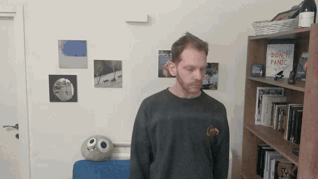 a man stands in front of a shelf with a book titled " do n't panic " on it