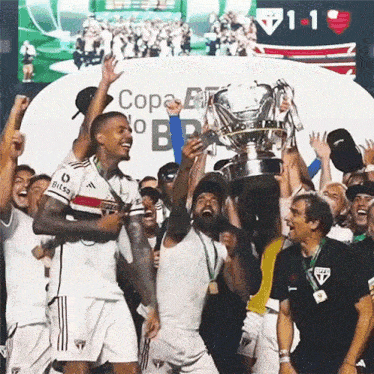 a group of soccer players are holding up a trophy in front of a sign that says copa no b