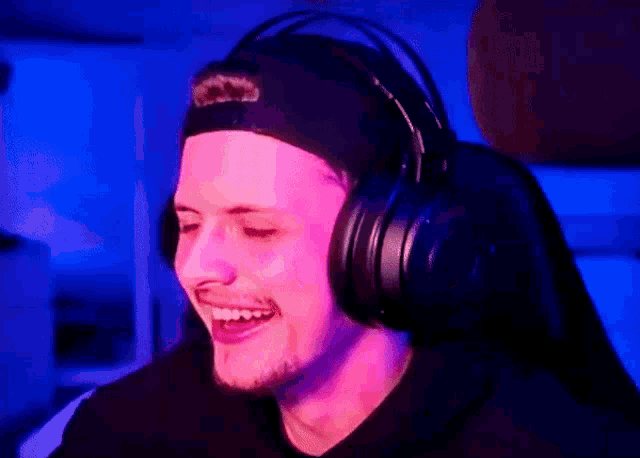 a man wearing headphones and a baseball cap is smiling .