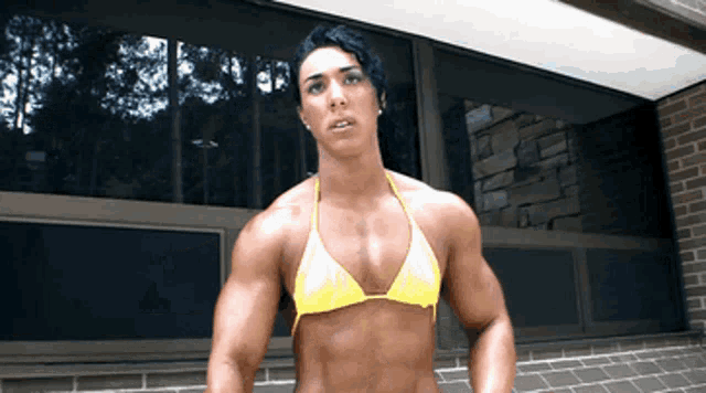 a woman in a yellow bikini is standing in front of a window