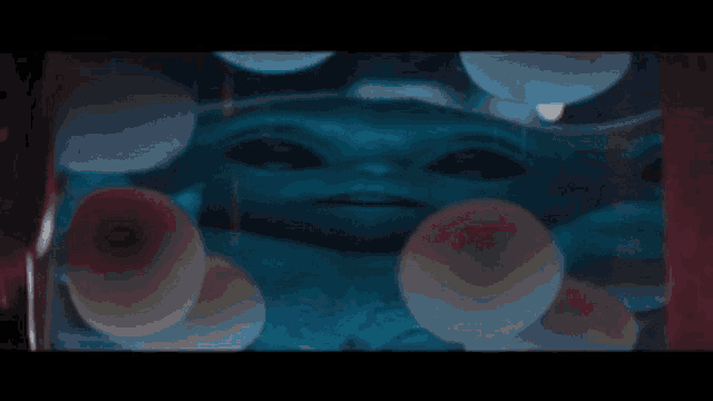 a baby alien is sitting in a glass container with balloons .