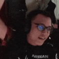 a man wearing headphones and glasses is sitting in front of a computer .