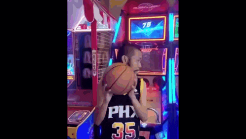 a man wearing a basketball jersey with the number 35 on it is playing a game in an arcade .