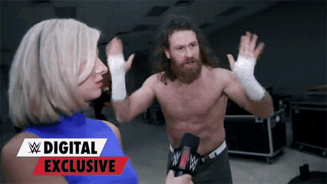 a man without a shirt is being interviewed by a woman with a digital exclusive banner behind them