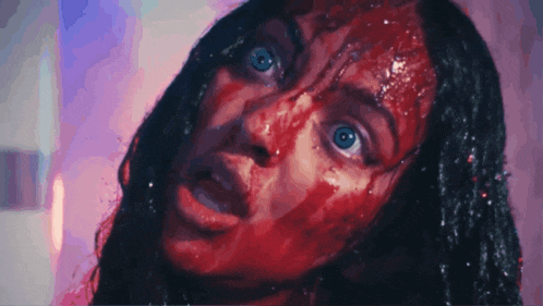 a woman with blood on her face is looking at the camera