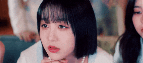 a close up of a girl 's face with short hair and a pearl necklace .