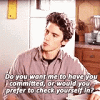 a man is sitting at a table in a kitchen talking to a woman .
