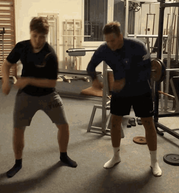 two men are dancing in a gym with one wearing a shirt that says twice