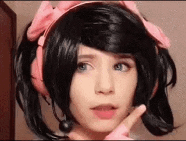 a girl wearing a wig and headphones is making a peace sign with her hand .