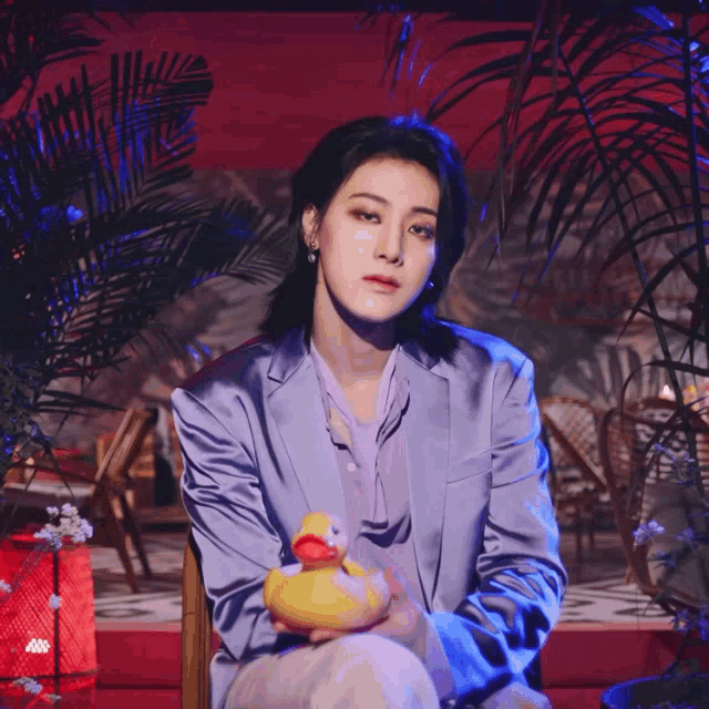 a woman in a purple suit holds a yellow rubber duck