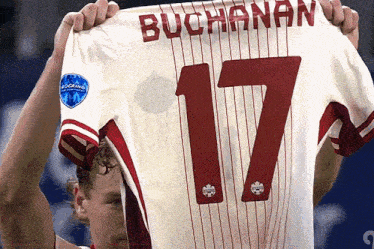a man is holding up a buchanan jersey