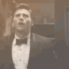 a man in a tuxedo and bow tie is standing in an elevator