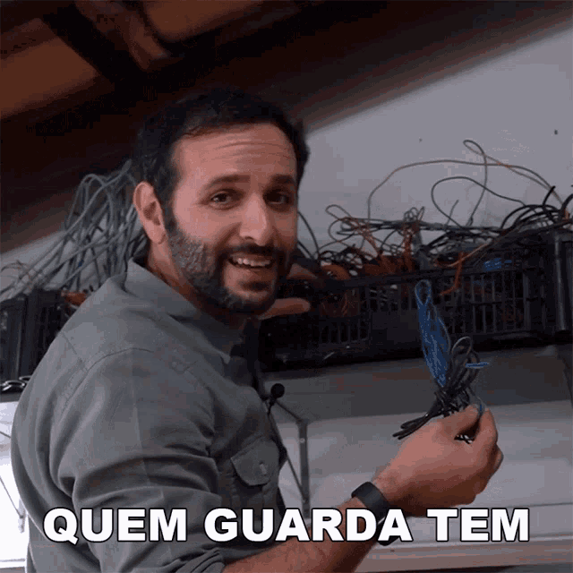 a man is holding a bunch of wires and the words quem guarda tem are on the bottom