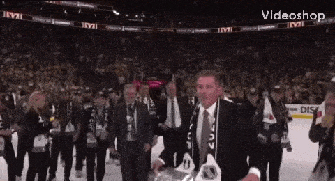 a man in a suit is holding a trophy in front of a crowd .