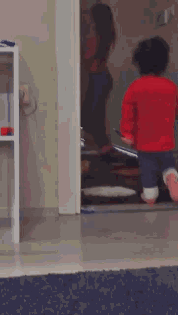 a little girl in a red sweater is running in a room