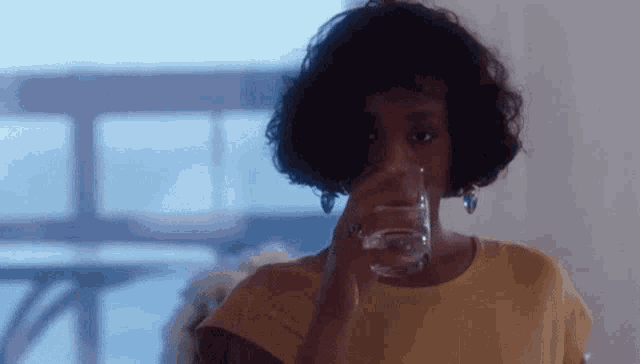a woman is drinking a glass of water in a room .