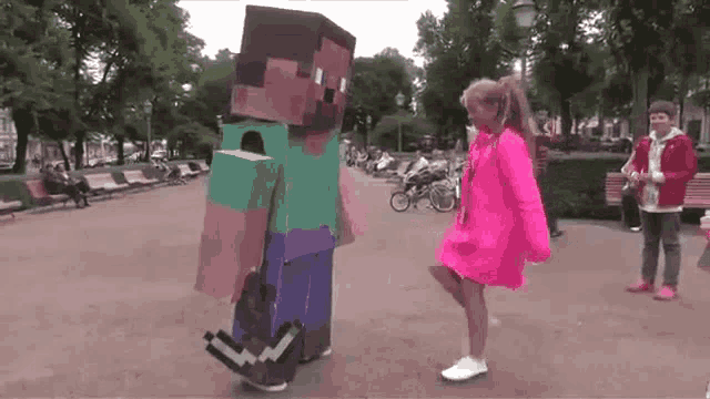a woman in a pink dress is standing next to a man dressed as a minecraft character .