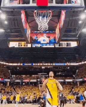 a basketball player in a yellow jersey is standing in front of a basketball hoop .